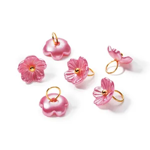 Close-up of iridescent pink pearlescent flower pendants with golden jump rings