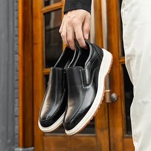 Business casual black leather loafers for men with stylish white soles held by hand