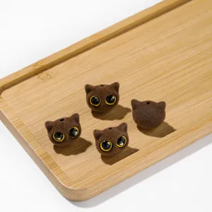 Détail macro de perles de chat floquées marron aux grands yeux pour bijoux DIY.