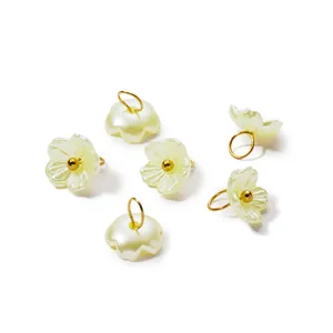 Macro view of iridescent pearl flower pendants with gold rings for DIY handmade jewelry.