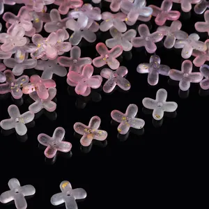 Detailed macro shot of frosted acrylic four-petal flower beads with gold foil and pink gradient