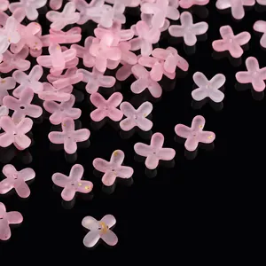 Macro detail of frosted pink acrylic flower beads with gold glitter for DIY jewelry.