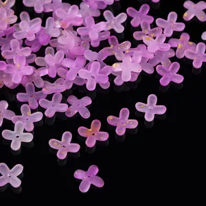 Detailed macro shot of purple frosted acrylic flower beads with gold foil splatter on black.
