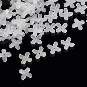 Macro detail of frosted white acrylic four-petal flower beads with gold foil accents.