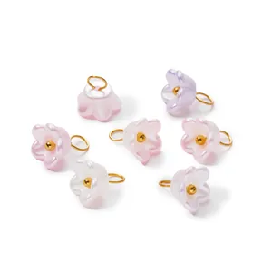 Detailed macro view of ABS pearlescent flower pendants with gold-colored metal jump rings
