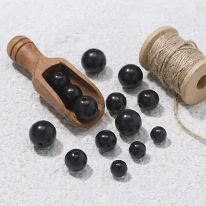 Macro view of black sandalwood beads with wooden scoop and spool for DIY jewelry