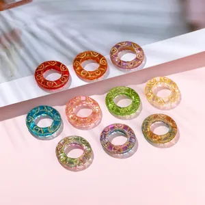 Close-up of colorful ice-transparent glass donut beads with intricate gold swirl patterns