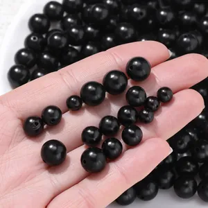 Hand showing various sizes of 6-10mm natural black sandalwood beads for DIY jewelry