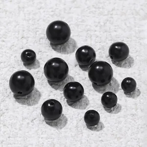 Close-up of polished black sandalwood beads with pre-drilled holes for DIY jewelry making