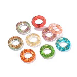 Group of colorful ice-transparent glass rings with gold swirl patterns for DIY jewelry.