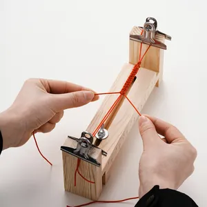 Hand an einem verstellbaren Holzwebwerkzeug zur Herstellung eines roten DIY-Armbands Foto.