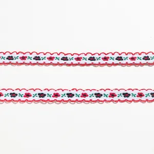Detailansicht des floralen Stickereibands mit rotem Wellenrand für kreative DIY-Bastelarbeiten