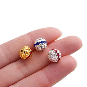 Vista detallada de cuentas espaciadoras huecas de 10mm con pedrería de colores en una mano