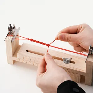 Detail des verstellbaren Holz-Webrahmens beim Flechten eines roten Armbands