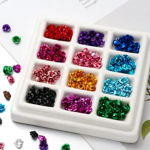 Detailed macro view of colorful 3D aluminum rose flower charms in a white sorting tray.