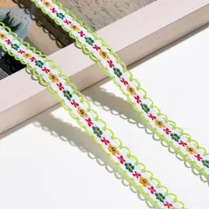 Detailaufnahme von weißem besticktem Blumen-Spitzenband mit grünen gewellten Kanten
