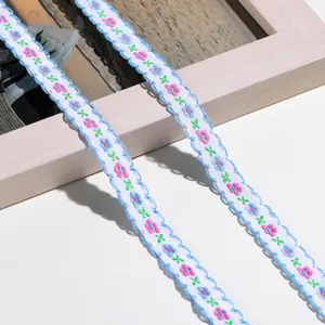 Nahaufnahme von Blumenbestickte Borte mit gewellten blauen Kanten und kleinen rosa Blüten