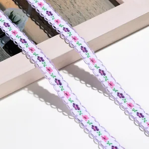 Makro-Detail von floral besticktem Webband mit lila Wellenrand für DIY-Projekte