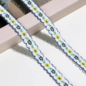 Nahaufnahme von fein besticktem Blumenband mit dunkelblauer Wellenborte für Bastelarbeiten