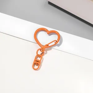 Gros plan d'un fermoir mousqueton en forme de cœur orange pour accessoires de porte-clés DIY