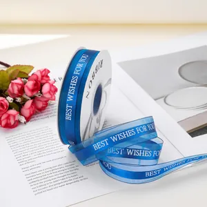Dettaglio macro del nastro di organza blu reale con testo 'Best Wishes' per pacchetti regalo