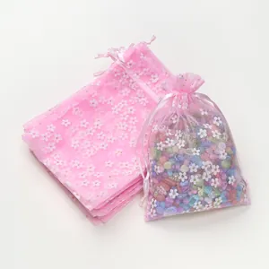 Roze organza zakjes met bloemen die de delicate print en de transparante netstructuur tonen