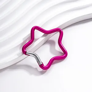 Gros plan d'un mousqueton en étoile magenta en aluminium sur une surface blanche ondulée.