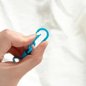 Primo piano di un moschettone blu macaron in lega di zinco aperto da una mano umana