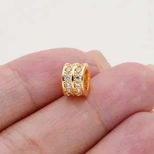 Detailed close-up of double row zirconia barrel bead charm in gold plating held on fingers