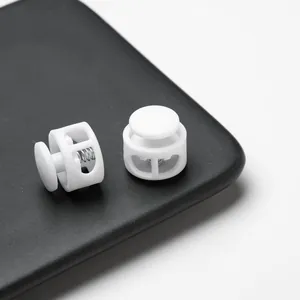 Close-up detail of durable white double-hole plastic spring cord locks for face masks