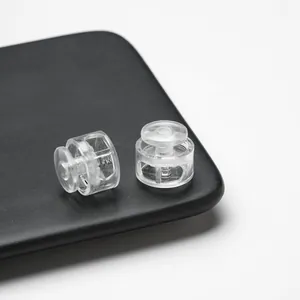 Detailed macro view of two clear plastic spring-loaded toggle cord locks on tray