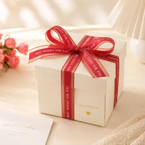 Dettaglio del nastro in organza rosso con bordi dorati e testo Best Wishes per regali