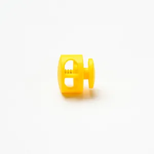 Macro detail view of a bright yellow plastic cord lock showing internal spring mechanism