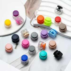 Close-up of colorful round plastic cord locks scattered on a clean white background.