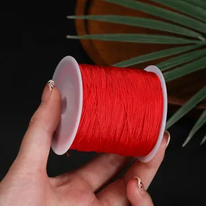 Gros plan d'une bobine de fil de jade rouge 0,4 mm pour le tissage de bijoux DIY.