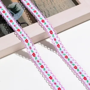 Nahaufnahme von besticktem Blumen-Spitzenband mit lilafarbenem Wellenrand und kleinen Blumen.