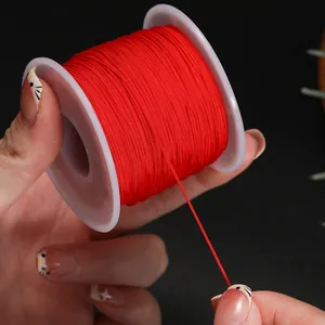 Gros plan d'une bobine de fil de jade rouge de 0,6 mm pour bijoux DIY et bracelets