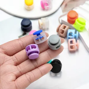 Close-up view of colorful round double-hole plastic spring cord buckles held in a person's hand