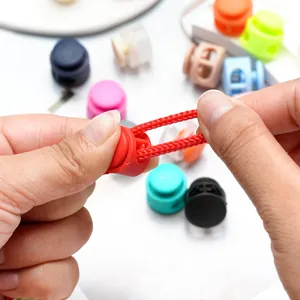 Close-up of double-hole plastic spring cord lock adjusting red elastic rope detail