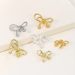 Detailed view of glossy gold and silver bow-knot beads for DIY jewelry making.