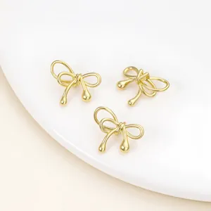 Close-up of three gold-plated bow beads for DIY jewelry making with smooth finish