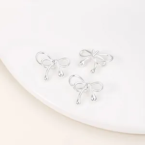 Macro detail view of three silver-tone polished bow-shaped beads for DIY jewelry design.