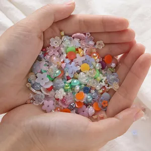 Close-up of assorted acrylic flower beads and mini pearls held in hands for DIY crafts