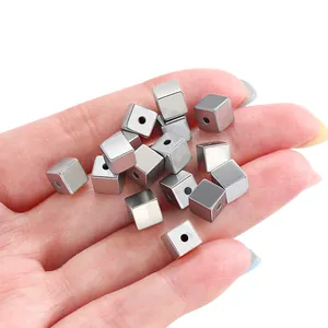 Metallic silver cube spacer beads held in hand showing fine detail for DIY jewelry making