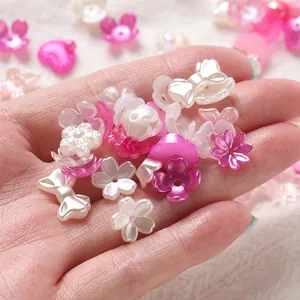 Detailed view of mixed pink and white pearly acrylic flower and bow beads for DIY nail art