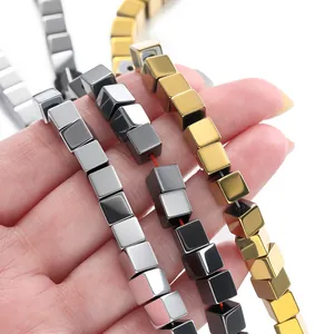 Macro detail of metallic hematite cube spacer beads in silver, black, and gold finishes