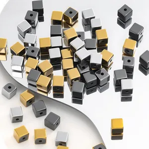 Macro view of hematite cube beads in black, gold and silver finishes for DIY jewelry.