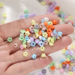 Gros plan de perles de muguet en acrylique coloré de 6 mm dans la main pour bijoux DIY