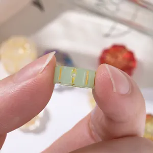 Detailed view of a celadon green glass bead with gold-painted patterns for DIY jewelry