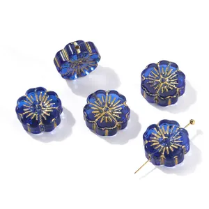 Detailed macro view of royal blue glass flower beads with delicate gold painted details.